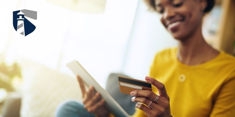 African American female holding a credit card in one hand and tablet in the other