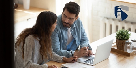 Man and woman talking while looking over bills on their laptop