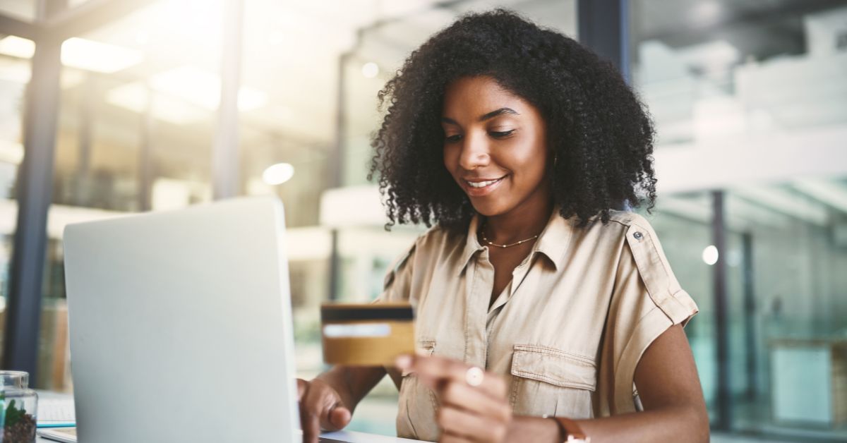 woman looking at credit card with laptop