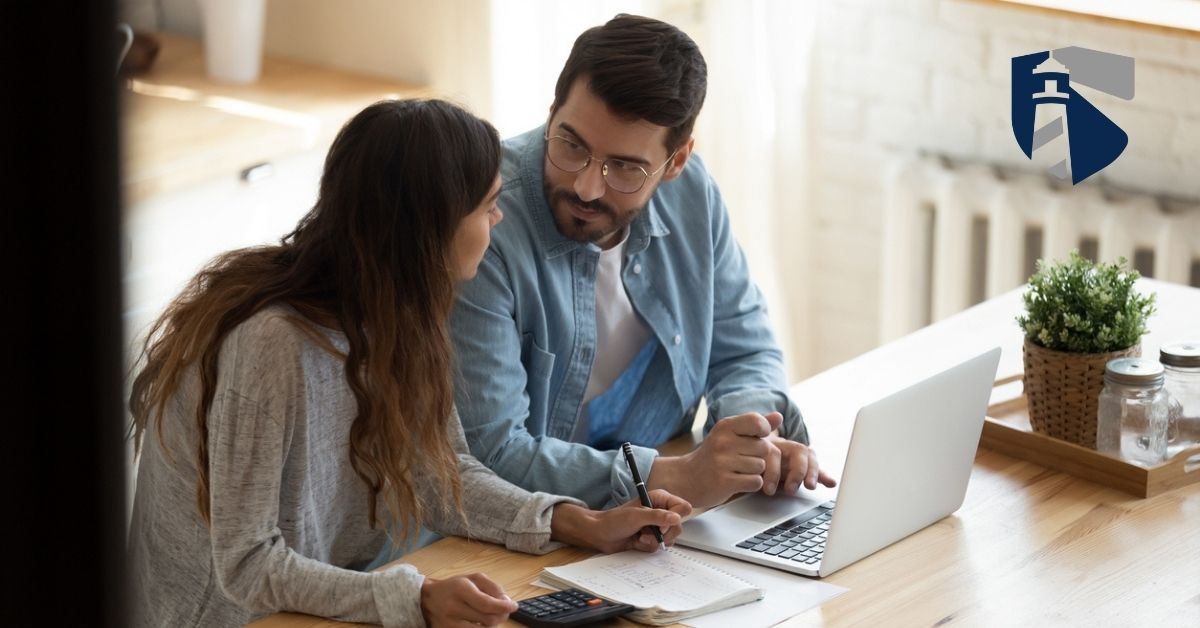 Man and woman talking while looking over bills on their laptop